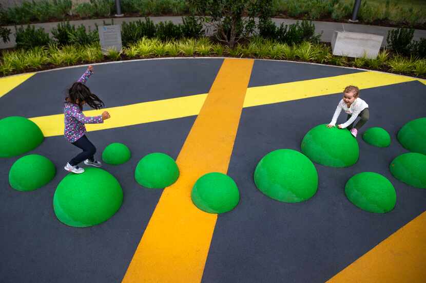 Cecilia Collins-Bratton (right) and Harper Trull jump on a playground following the opening...