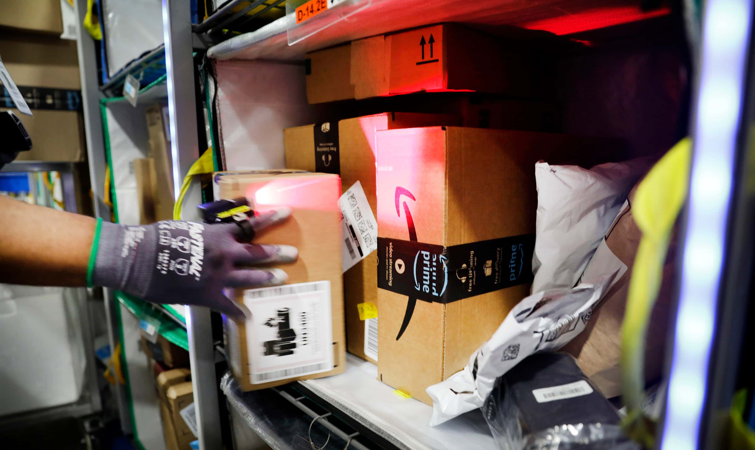Crew member Fabian Ugwunwa uses a laser to identify the appropriate tote to stow early PRIME...