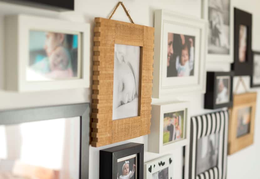 Brown, black and white picture frames with family photos displayed on a white wall