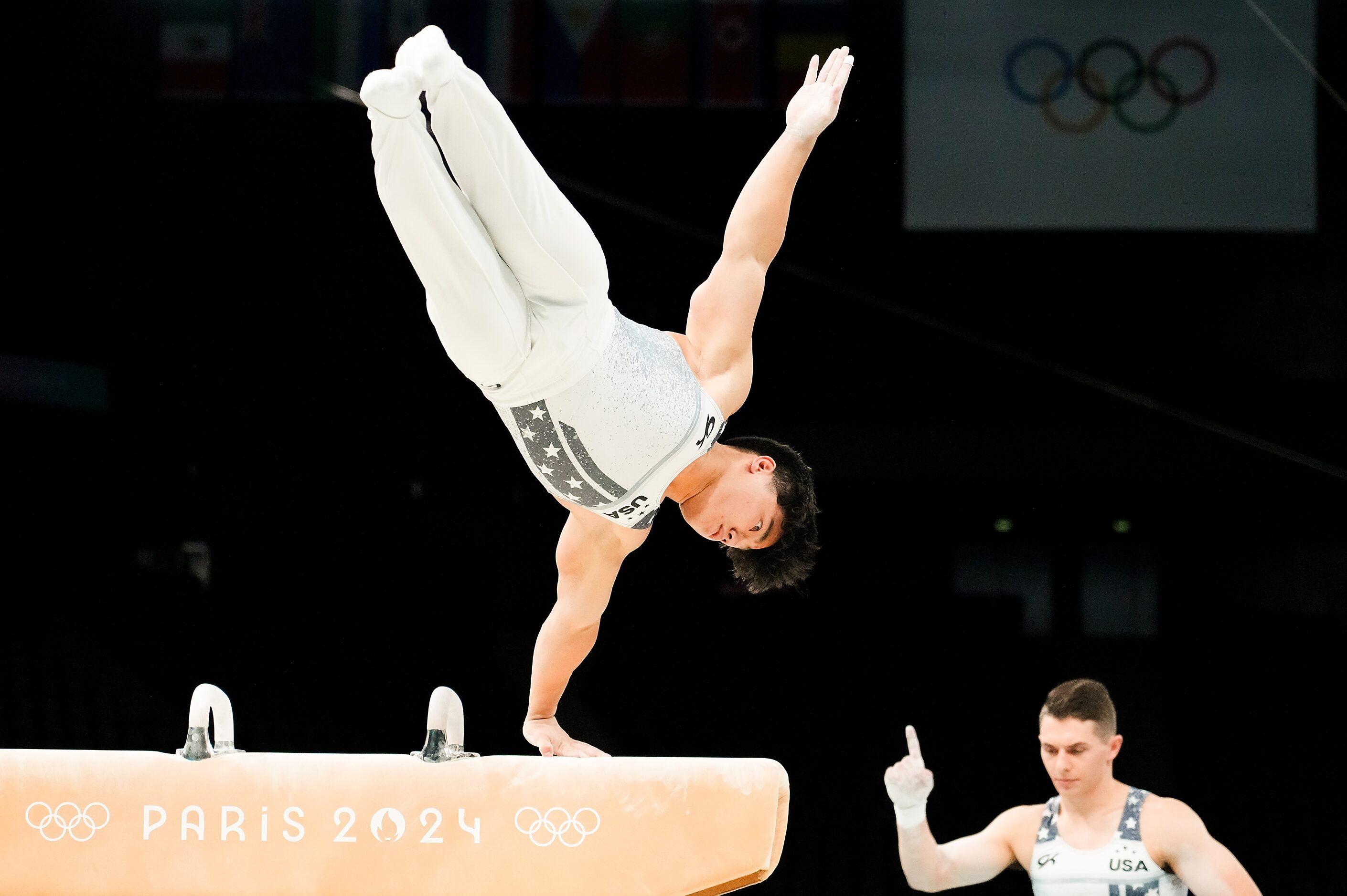 Asher Hong of the United States works on the pommel horse as teammate Paul Juda cheers him...