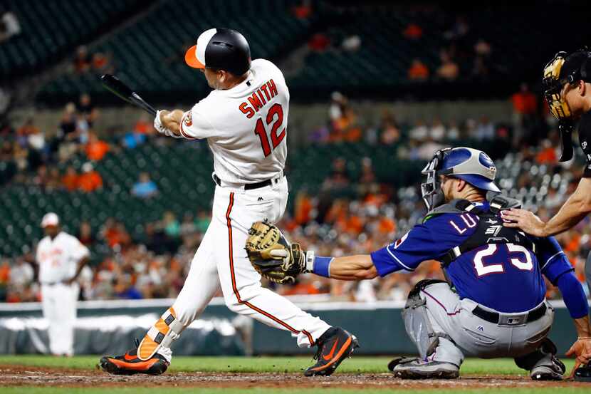 Baltimore Orioles' Seth Smith hits a solo home run in front of Texas Rangers catcher...