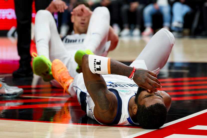 Dallas Mavericks guard Kyrie Irving lies on the court after falling during the first half of...