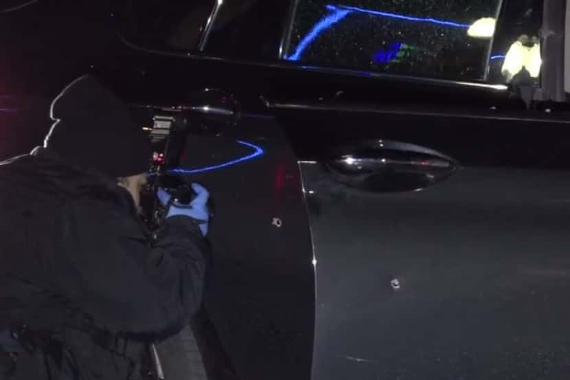 A police photographer shoots photos of a car that was hit in a drive-by shooting Friday...