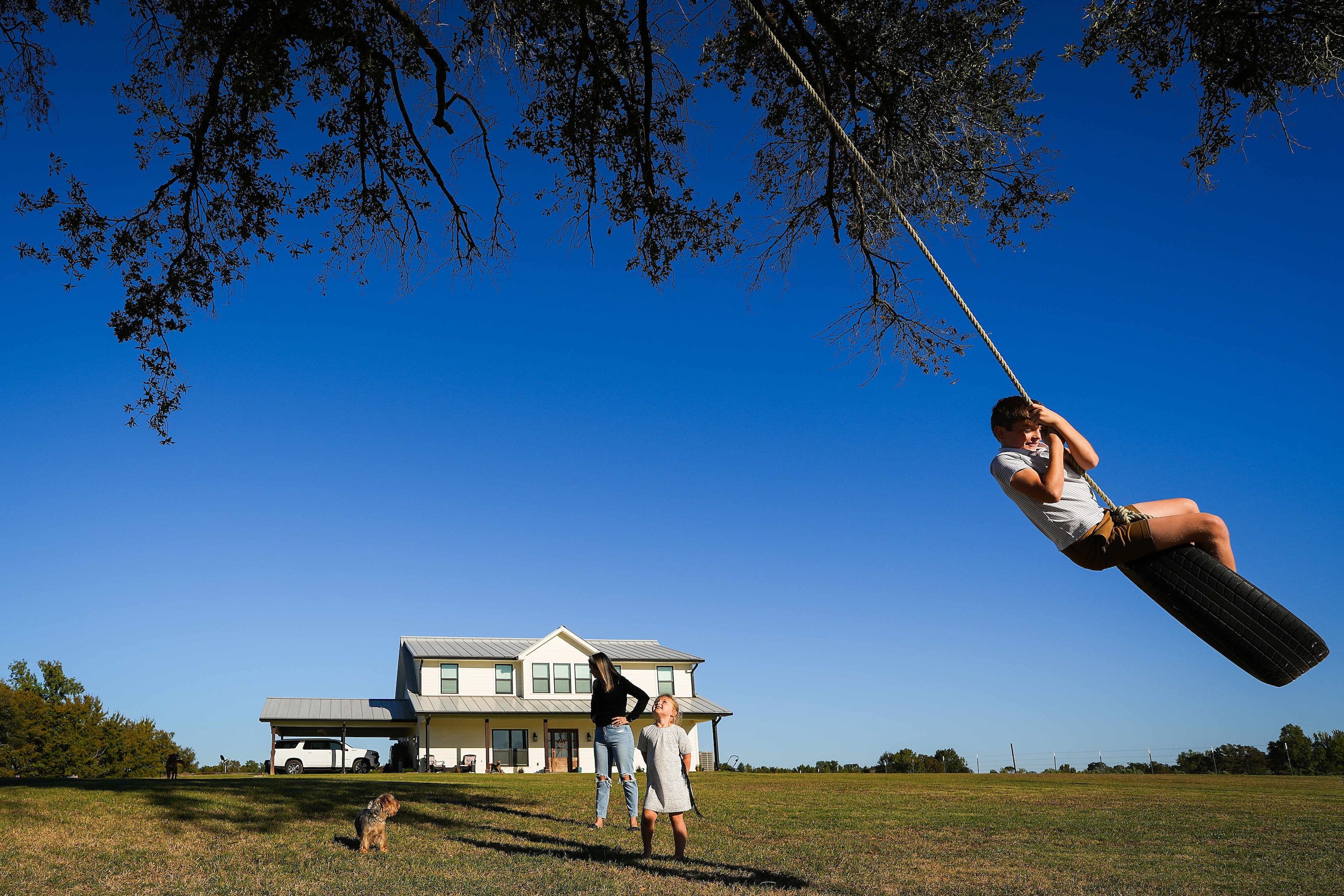 Reid Rolen, 9, plays on a tire swing as his sister Lyla, 5, and his mother Mandi Rolen look...