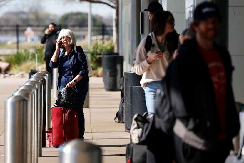 Passengers remain on their cell phones at the ride share section of Dallas Love Field, on...