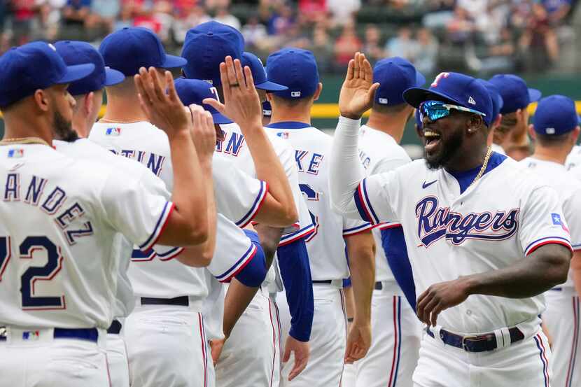 Texas Rangers right fielder Adolis Garcia (53) high fives relief pitcher Jonathan Hernandez...