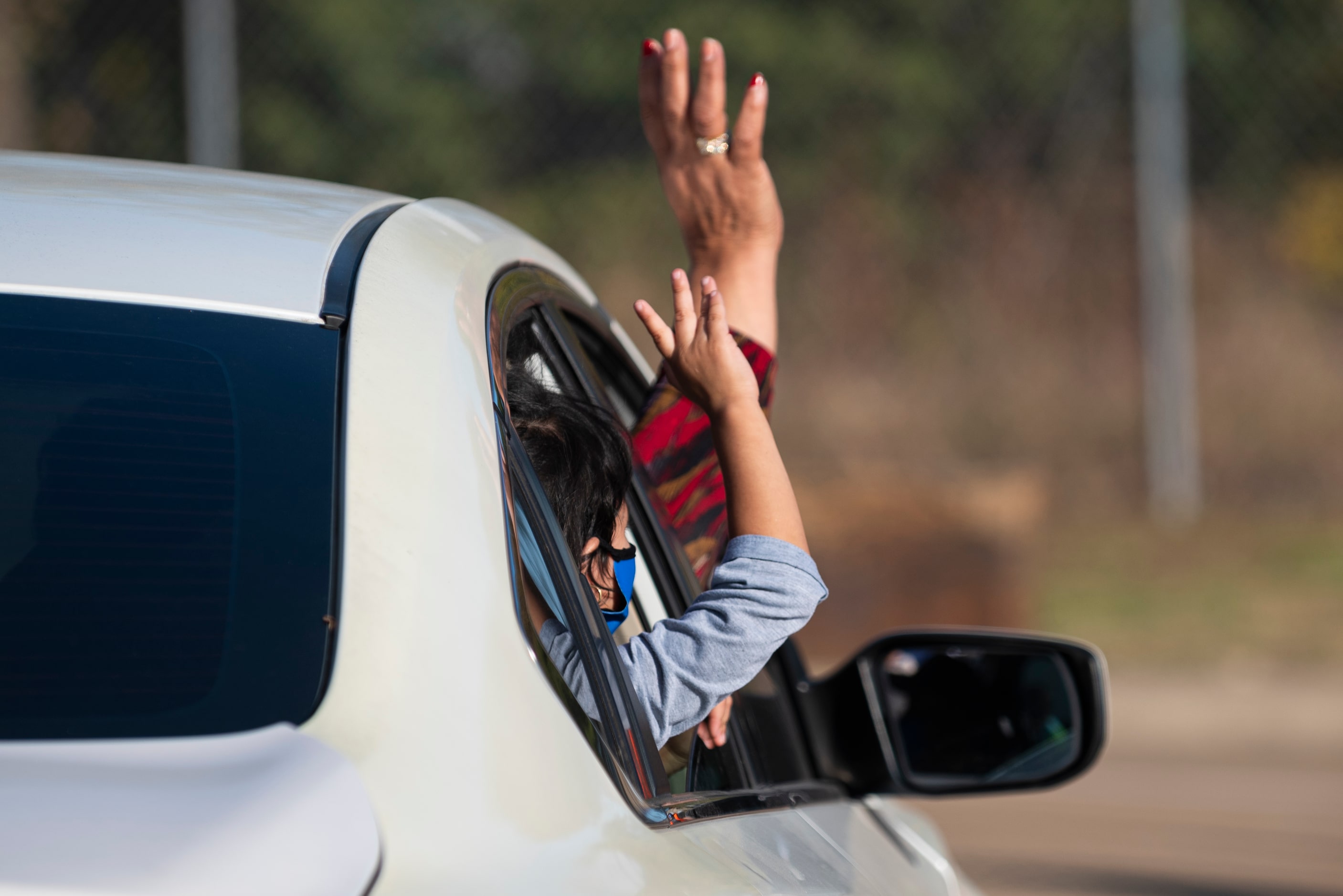 A woman and young girl wave goodbye to Mavs players and volunteers as they thanked them for...