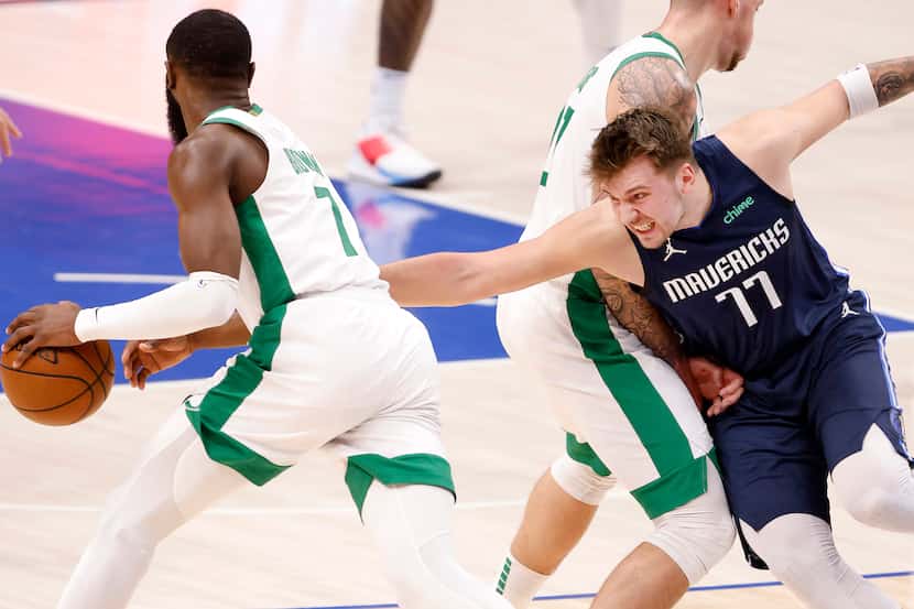 Dallas Mavericks guard Luka Doncic (77) reaches for Boston Celtics guard Jaylen Brown (7) as...