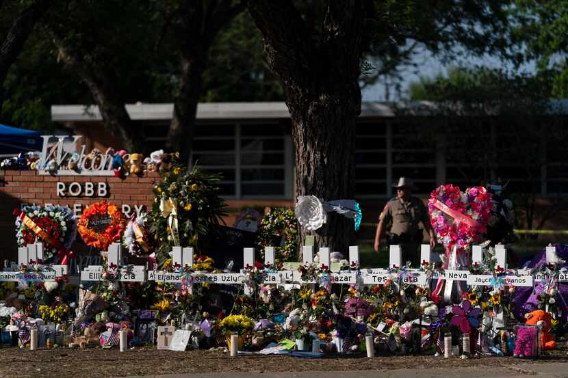 Flowers and candles are placed around crosses on May 28, 2022, at a memorial outside Robb...