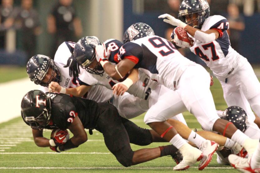 Euless Trinity's Joel Kimpela (22) is brought down by a host of Allen defenders during the...