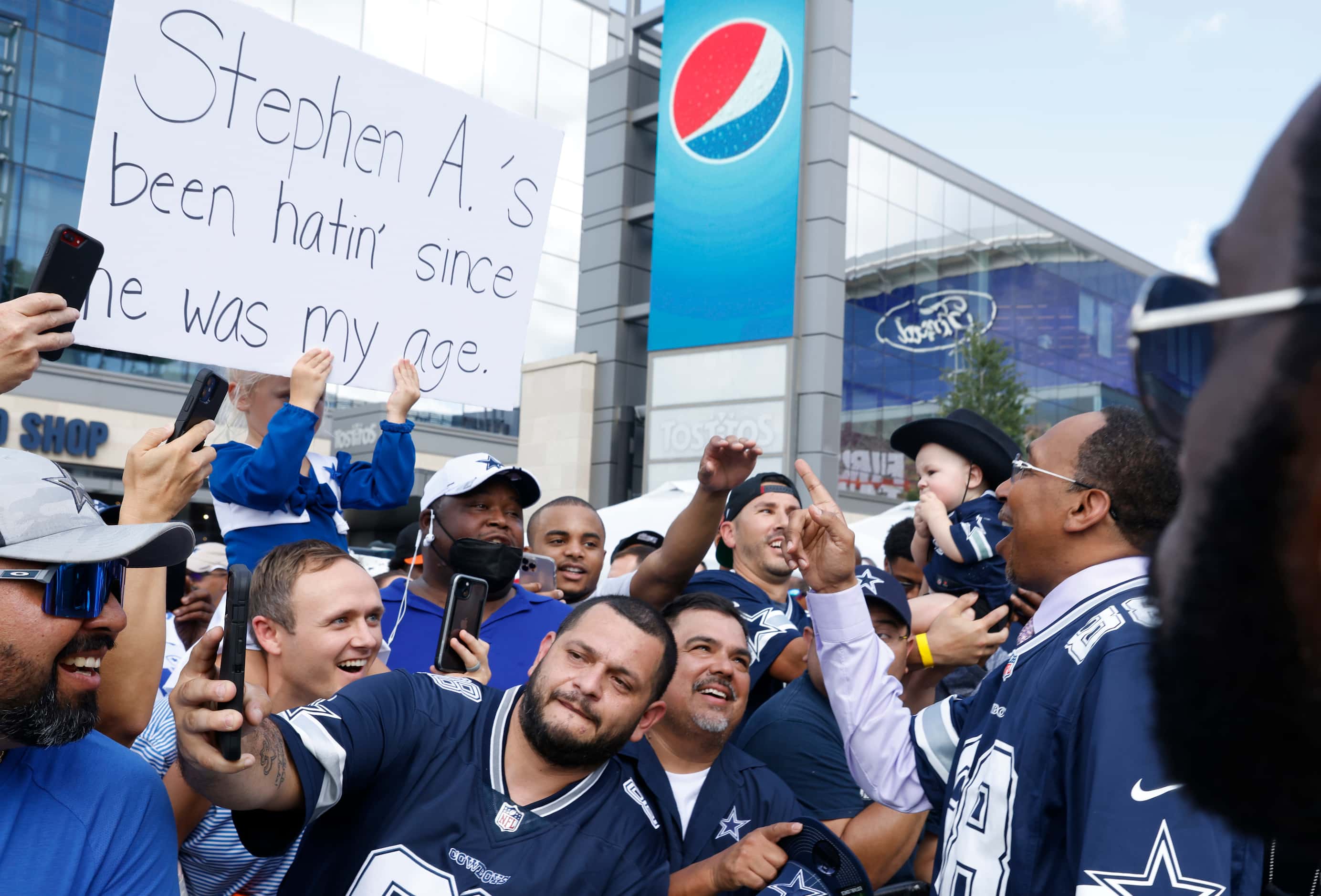 Host Stephen A. Smith also known as a "Cowboys Hater,” right, reacts towards a sign held by...