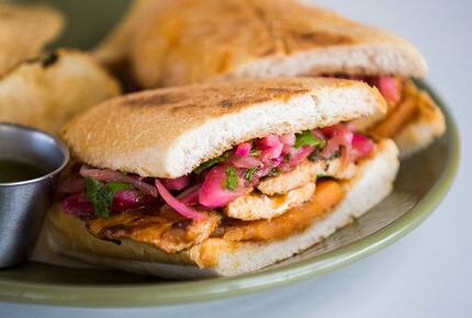 A Peruvian sandwich with pork loin, charred sweet potato and citrus onions on bolillo bread...