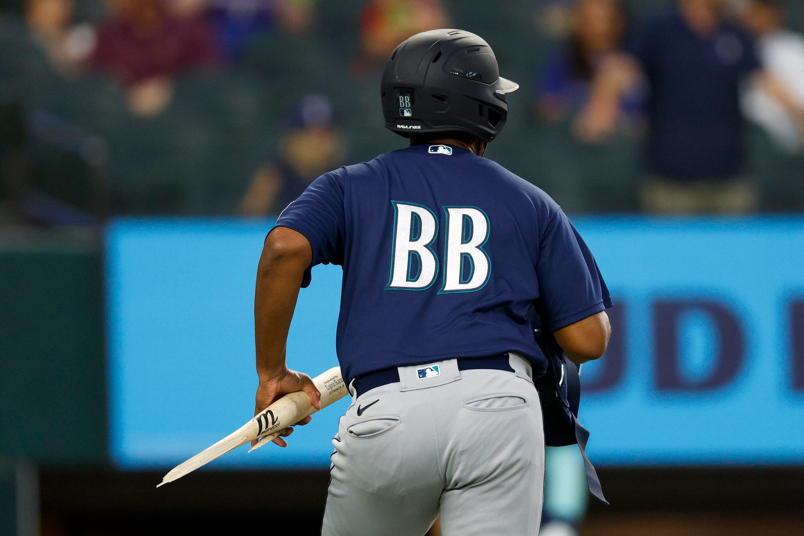 A Seattle Mariners ball boy carries away a broken bat that stuck Texas Rangers starting...