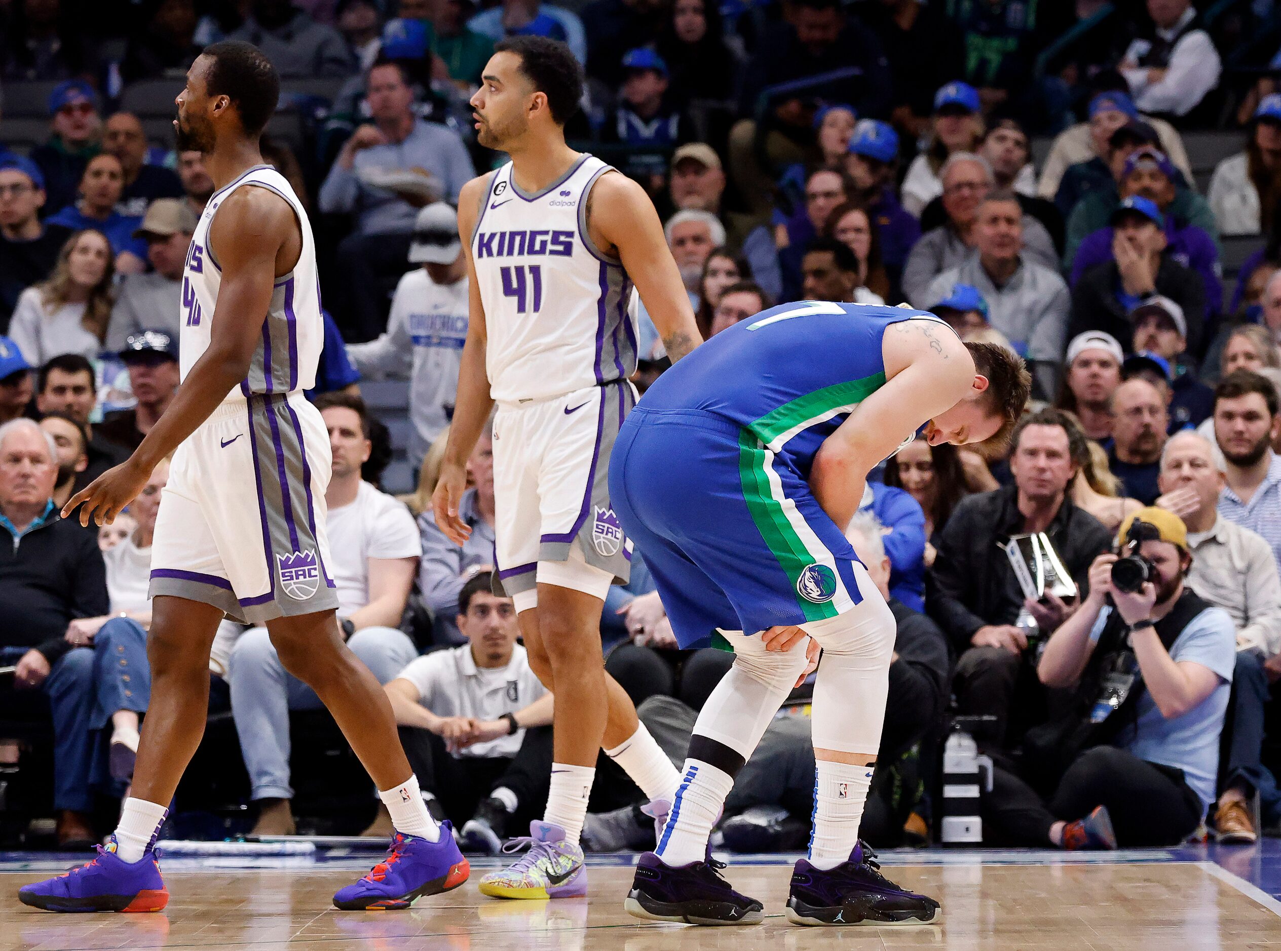 Dallas Mavericks guard Luka Doncic (77) holds his left knee after colliding with Sacramento...