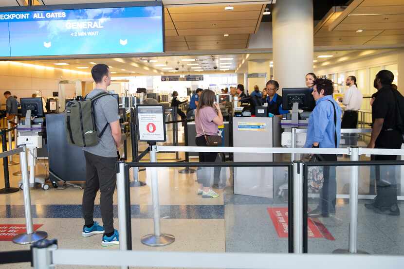 Un grupo de viajeros hacen fila para pasar por el control de TSA en la terminal D del...