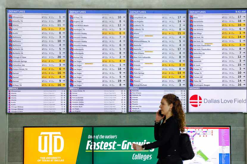 A traveler walks by a departure board at Dallas Love Field Airport in Dallas on Thursday,...