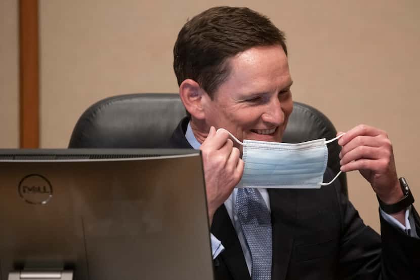 Dallas County Judge Clay Jenkins switches masks during a Dallas County Commissioners Court...