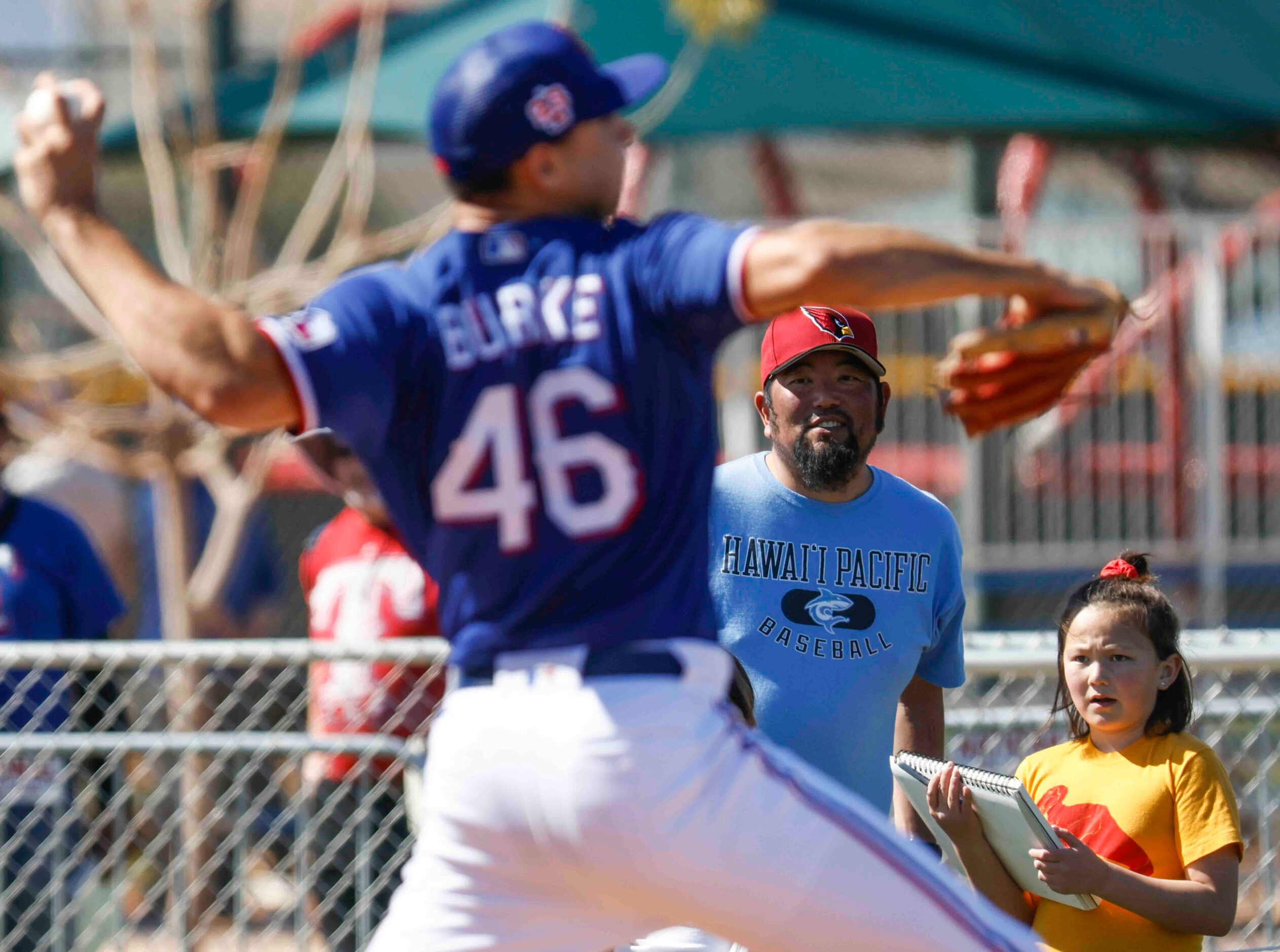 Crowd watches as Texas Rangers pitcher Brock Burke throws a pitch during a spring training...