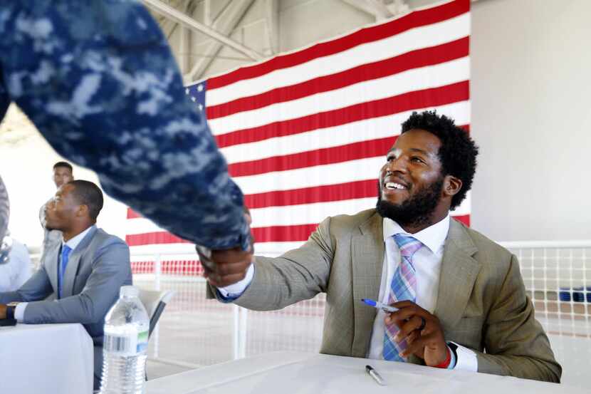 Dallas Cowboys running back Alfred Morris (right) shakes the hand of military personel...
