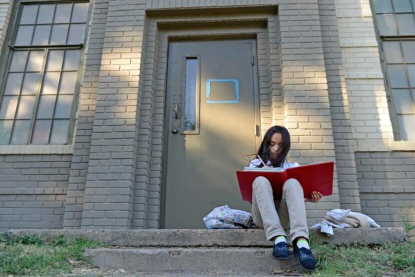 
Vanessa Rebulloso, 9, does her homework after school outside the Bataan Community Center,...