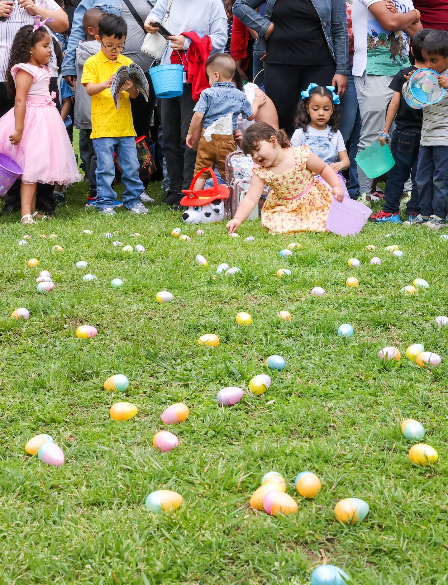 Kids eye the eggs laid out in front of them as they wait for the start of an egg hunt at the...