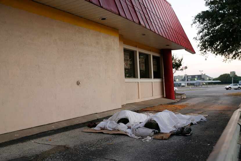 Two homeless men sleep in the driveway of a closed payday loan store located at 6534 East...
