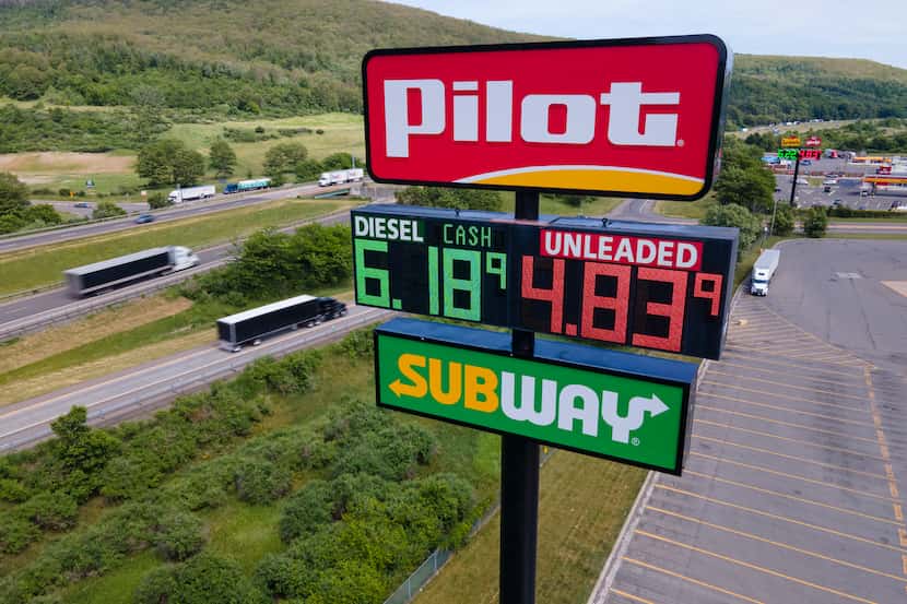 Trucks and cars drive by a Pilot Travel Center sign displaying fuel prices on June 20, 2022,...