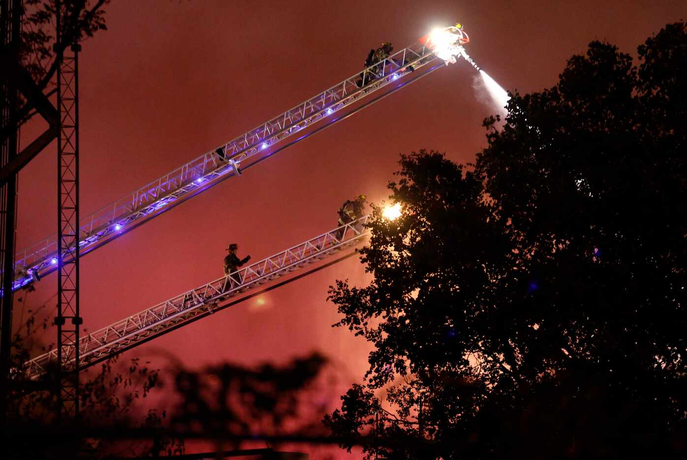 Dallas firefighters using aerial ladders battle a four-alarm business fire in the Fair Park...