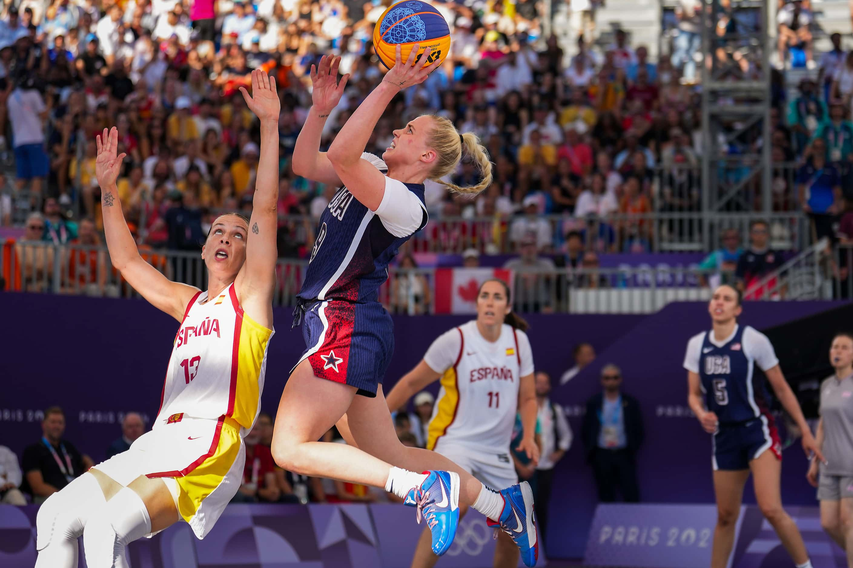 Hailey van Lith (9) of the United States scores past Spain’s Sandra Ygueravide (13) during a...