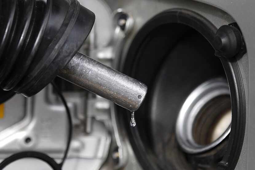 FILE - In this Thursday, Feb. 23, 2012 file photo, gasoline drips from a nozzle at gas...