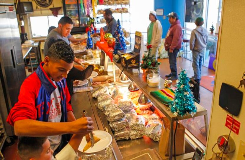 
Joseph “J.J.” Contreras gave 6-year-old Lucas Ruiz a hand plating tamales Thursday at East...