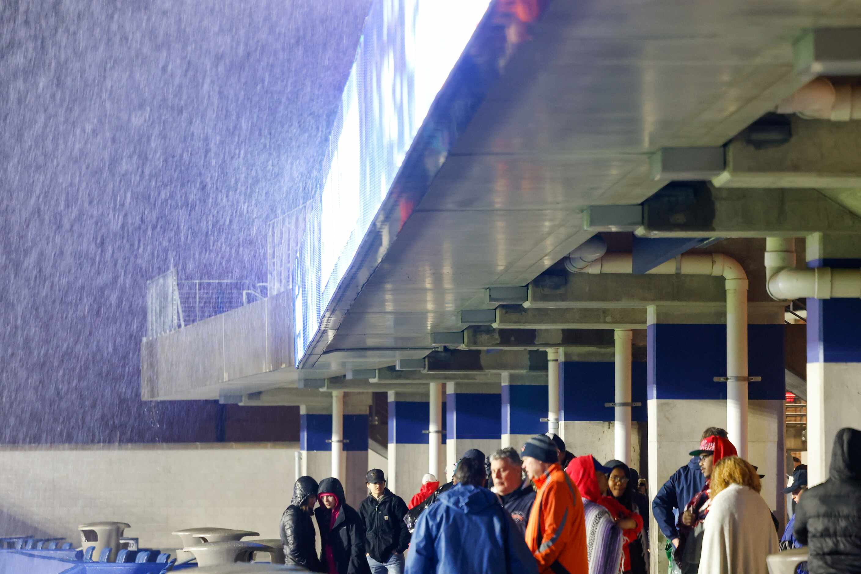 Bulldogs fans take shelter from the rain and lightning on the concourse level of the stadium...