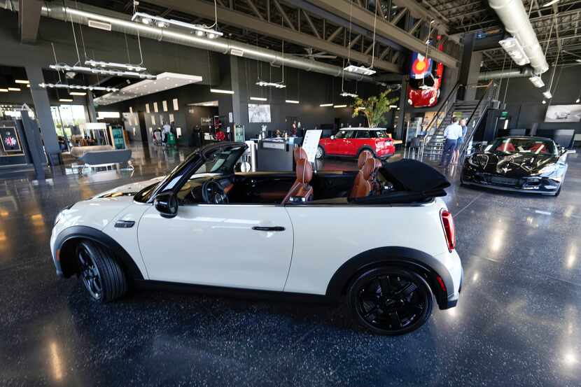 FILE - A sales associate talks with a prospective buyer of a Cooper SE electric vehicle on...