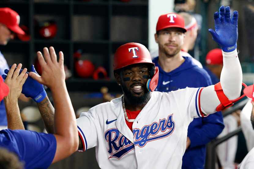 Texas Rangers right fielder Adolis Garcia (53) high fives teammates after hitting a home run...