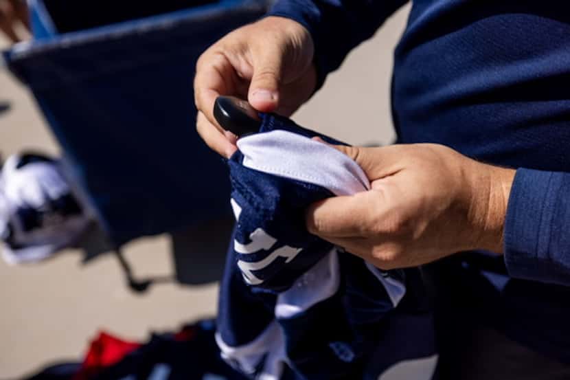 A member of the Cowboys training staff removes a GPS tracking device from a jersey. Players...