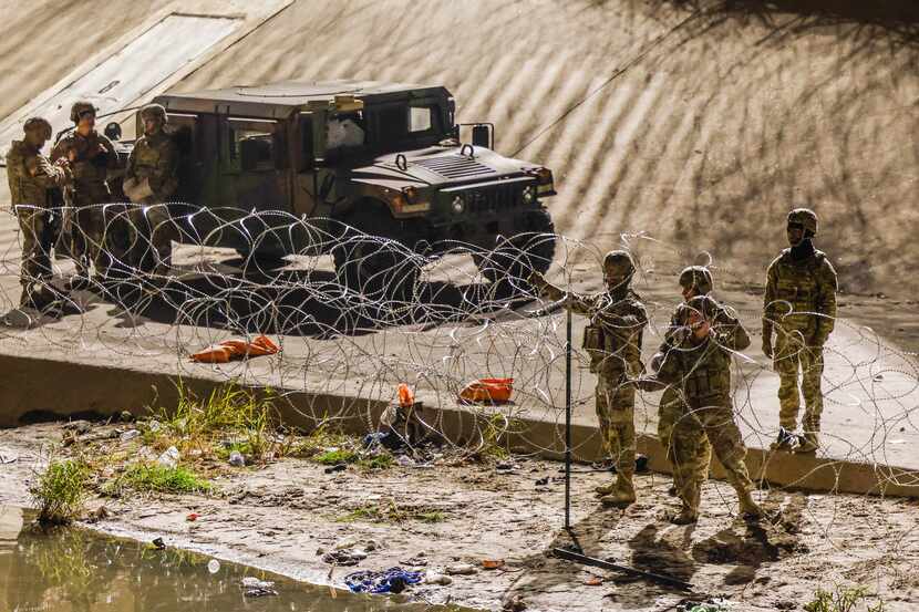Texas National Guardmen work on extending the barricade on the U.S. side of the border in El...
