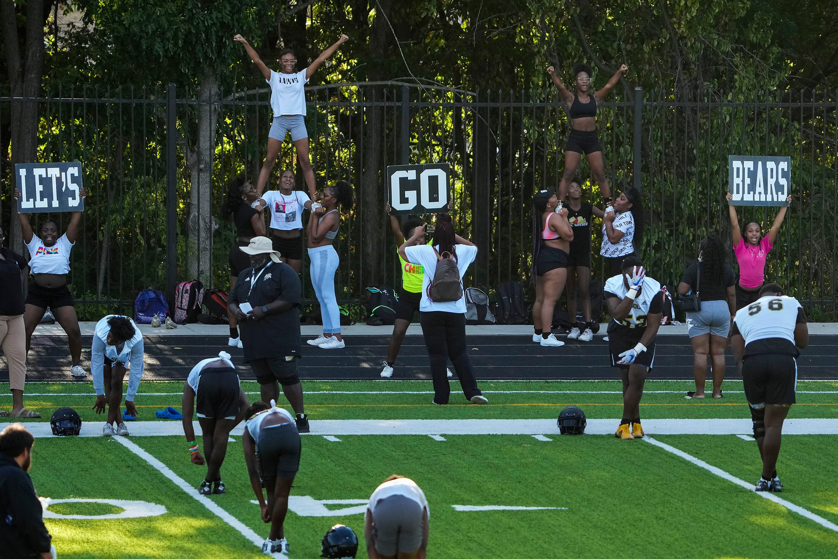 Cheerleaders chat “Let’s Go Bears” as players stretch during the first practice of the...