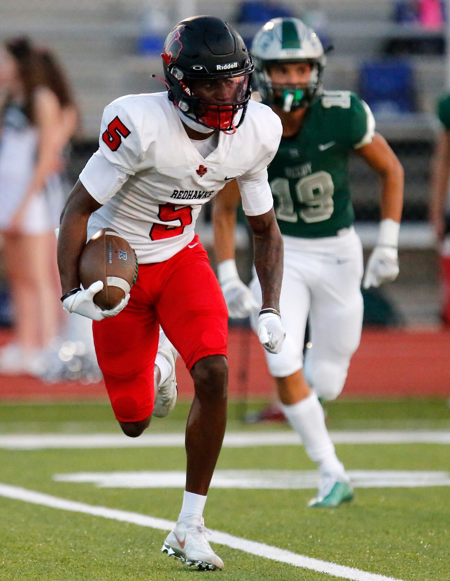 Liberty High School wide receiver Evan Stewart (5) carries the football and is chased by...