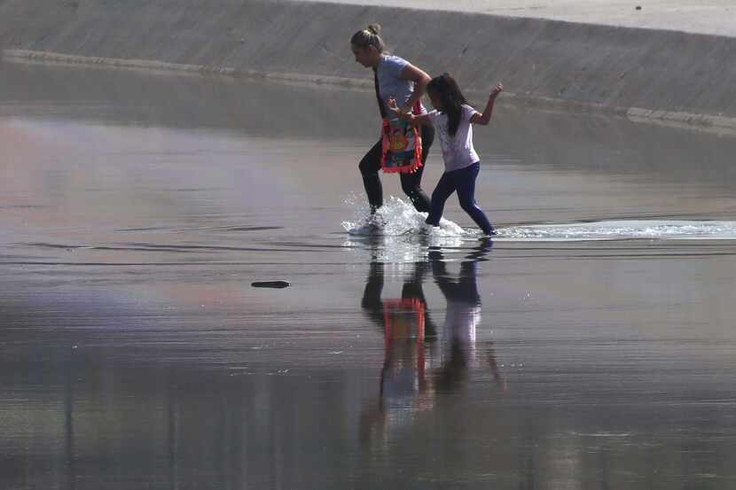 A woman and a child from Venezuela cross the Rio Grande from Ciudad Juárez, Mexico into El...