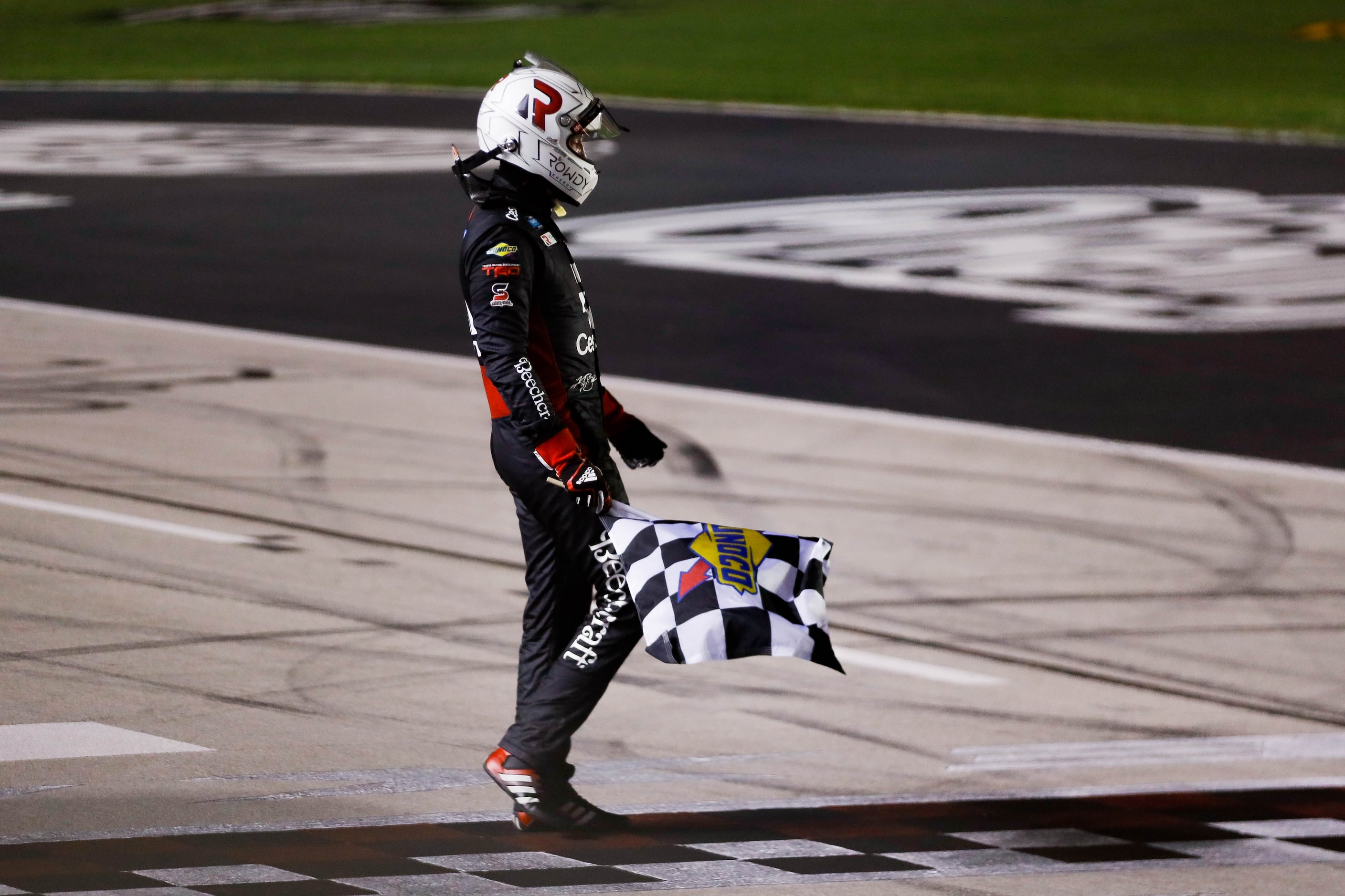 Driver Kyle Busch (No. 51) holds the race flag after winning the Vankor 350 NASCAR Gander RV...