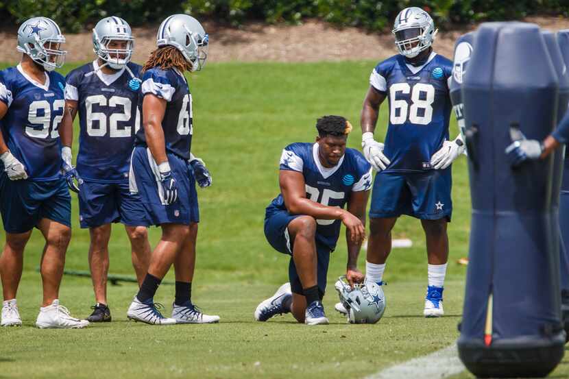 Dallas Cowboys defensive tackle David Irving (95) kneels to the side and watches teammates...