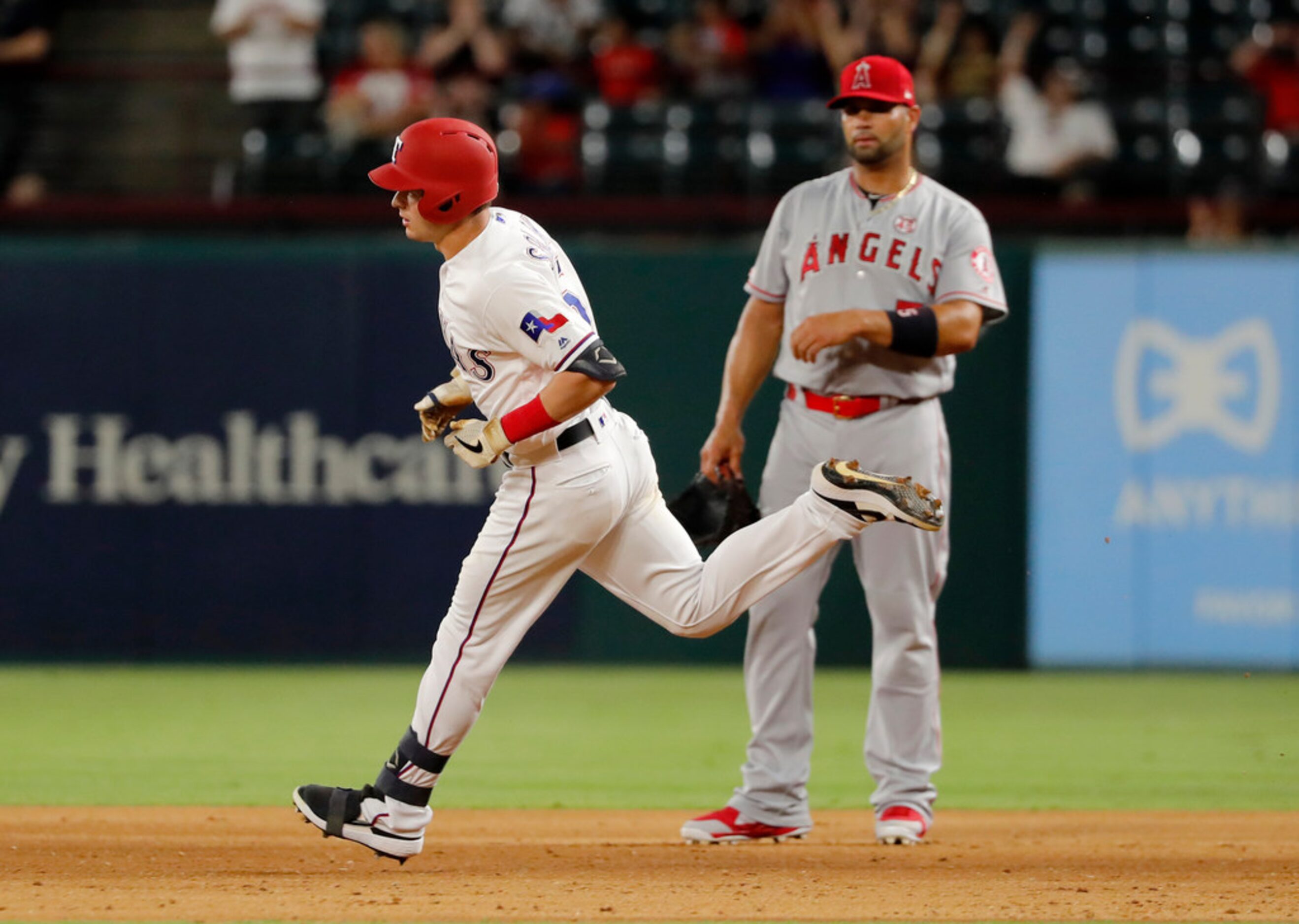 Texas Rangers' Nick Solak, front, runs past Los Angeles Angels' Albert Pujols after hitting...