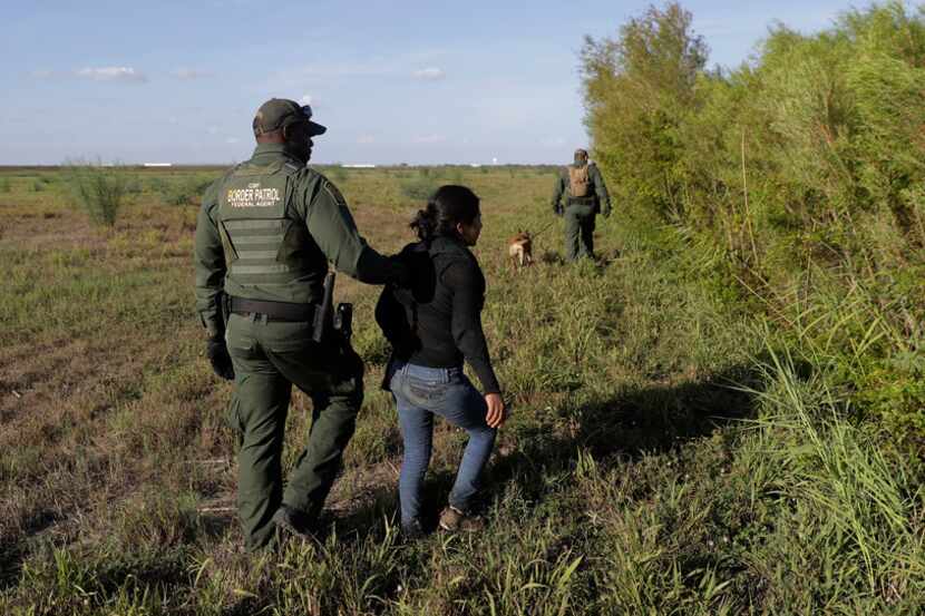 In this Aug. 11, 2017, photo a U.S. Customs and Border Patrol agent escorts an immigrant...