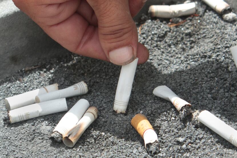 A smoker snuffs out a cigarette in a public space where smoking is allowed.