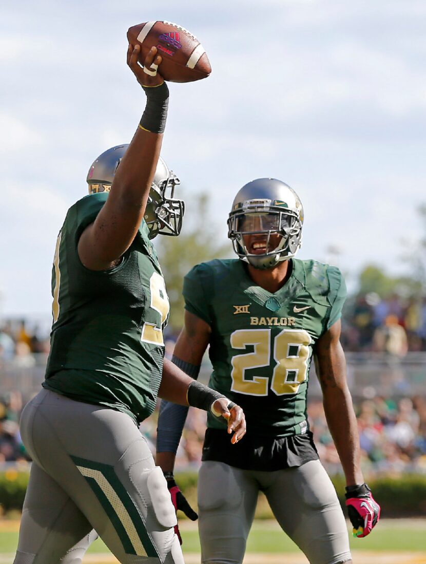 Baylor defensive tackle Ira Lewis (97) holds up the ball next to safety Orion Stewart (28)...