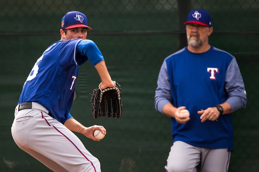 Texas Rangers starting pitcher Cole Hamels throws in the bullpen under the eye of pitching...