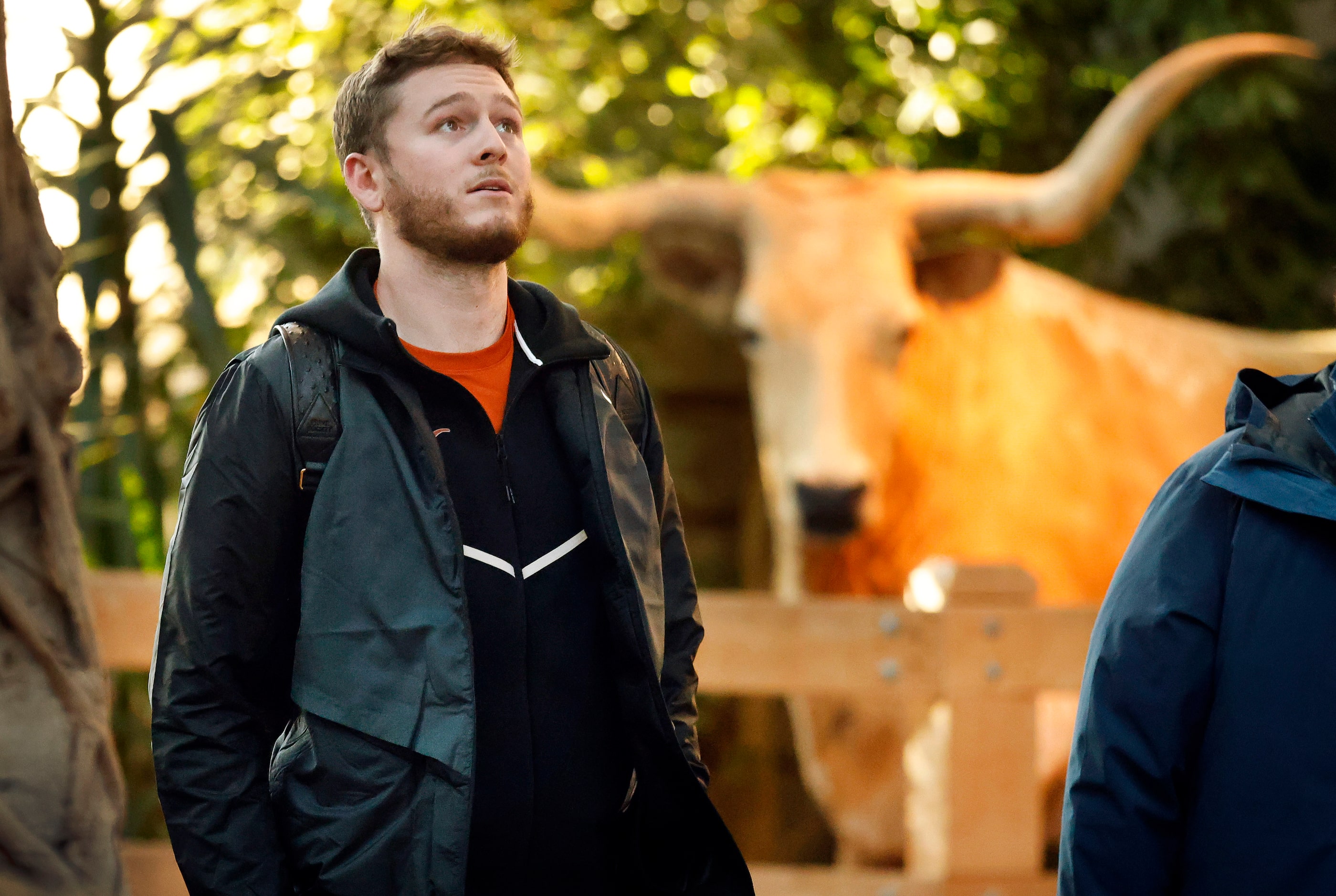 Passing a mounted longhorn, Texas Longhorns quarterback Quinn Ewers looks up at the large...