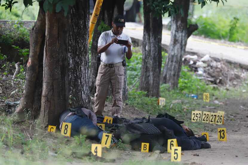 Un policía de la Fiscalía General toma fotografías de los cuerpos de policías asesinados en...