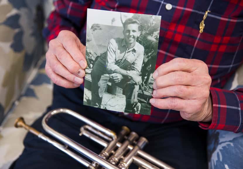 John Gould holds a photo of himself from his World War II days and his beloved trumpet, an...