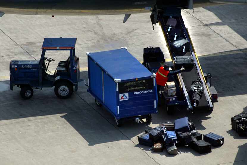 ORG XMIT: *S0405533084* Tuesday, March 11, 2003   #44340
A baggage handler unloads luggage...